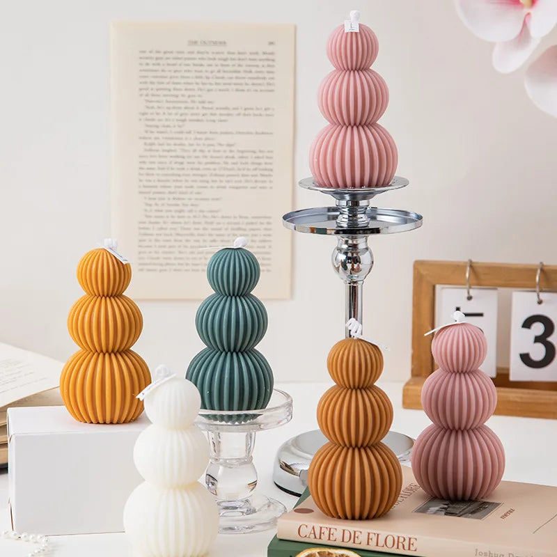 Decorative candle holders with ribbed design on a table with books and a calendar in the background.