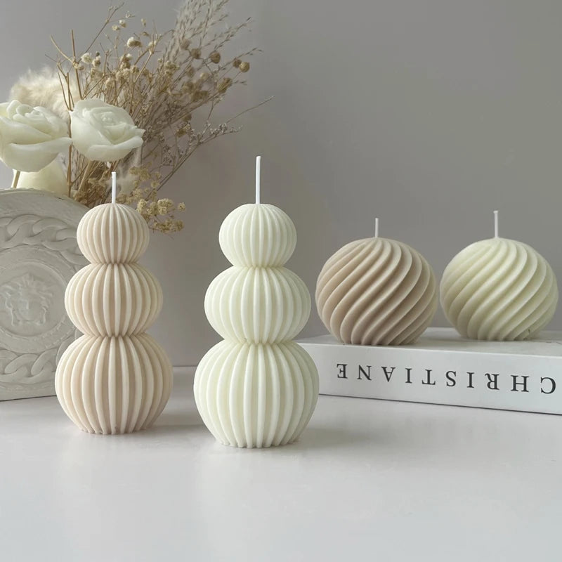 Three textured candles on a white surface with a book and decorative elements in the background.