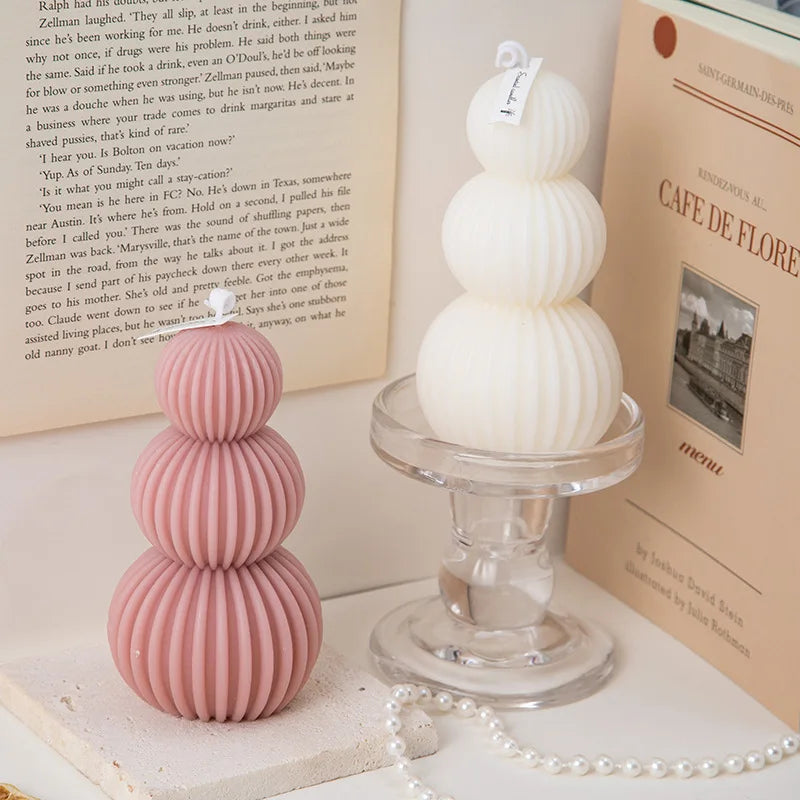 Two stacked ceramic items, one pink and one white, on a clear stand with books in the background.