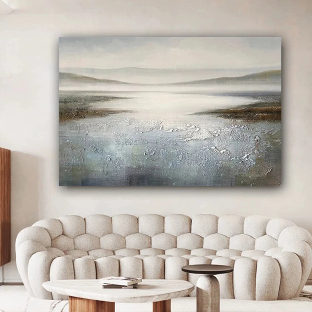 Abstract landscape painting on a wall above a beige sofa in a living room.