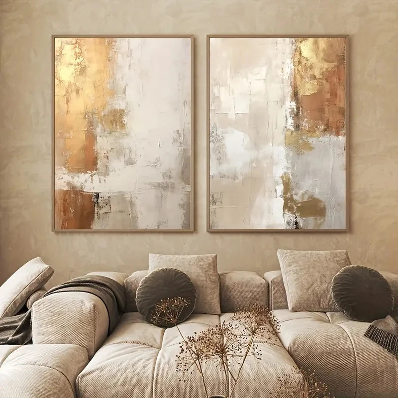 Two abstract paintings on a wall above a beige sofa with decorative pillows.