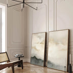 Two abstract art pieces on a wall in a stylish room with a chair and decor.