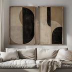 Two abstract art pieces on a wall above a beige sofa.
