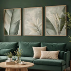 Green sofa with decorative pillows in a living room with framed botanical art on the wall.