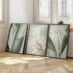 Three framed botanical prints on a wooden floor with light-colored walls and windows in the background.