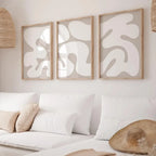Three abstract wall art pieces on a white wall above a sofa.