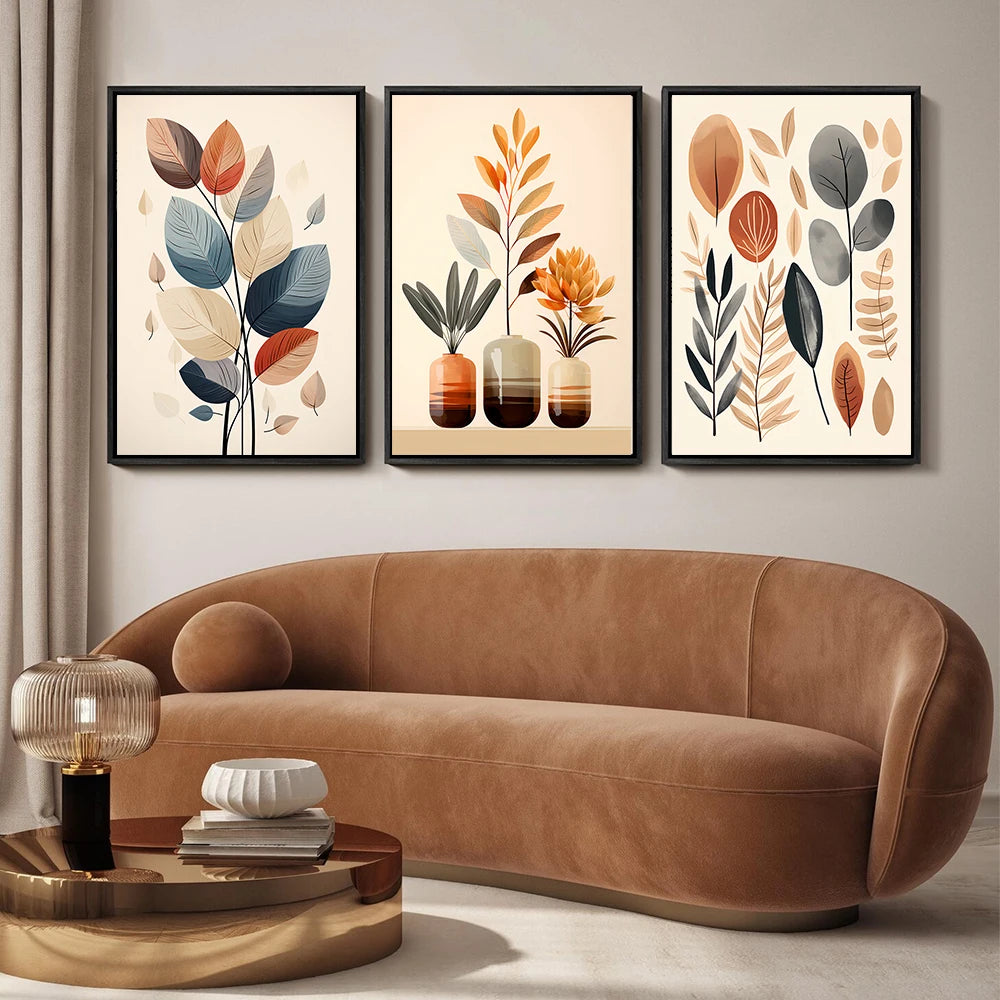 Brown sofa in a living room with three framed leaf art pieces on the wall.