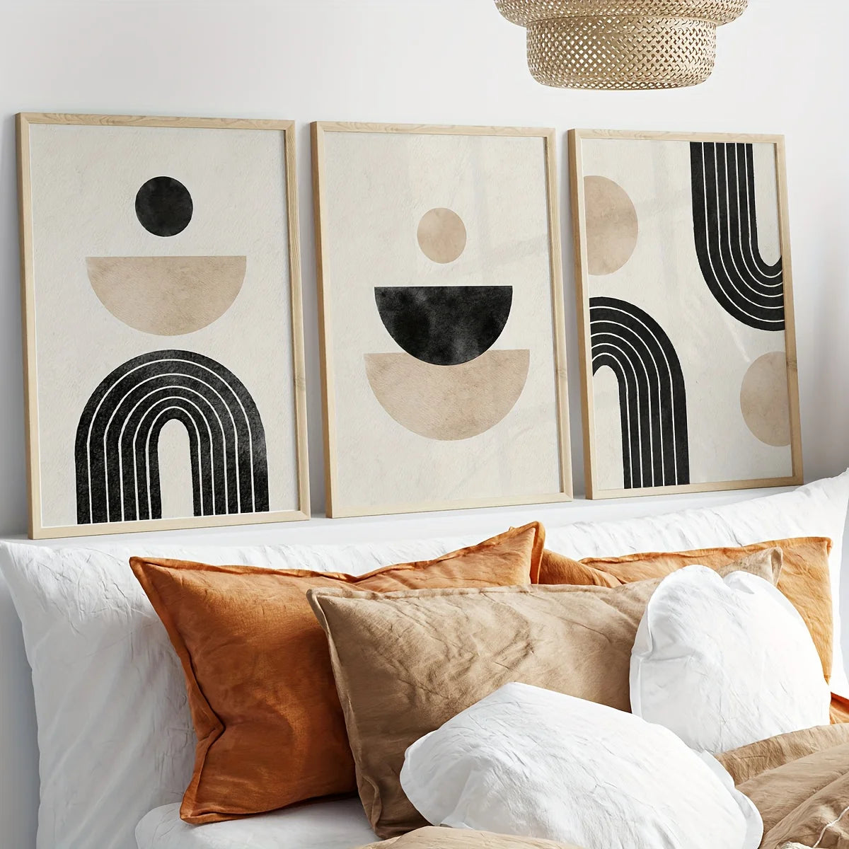 Three abstract art pieces on a wall above a sofa with decorative pillows.