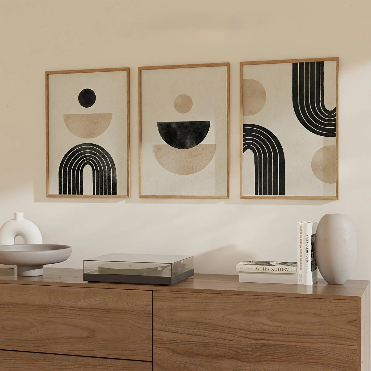 Three abstract framed artworks on a wall above a wooden cabinet with decorative items.