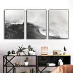 Three framed black and white wave artworks on a wall above a shelf with decorative items.
