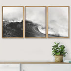 Three framed prints of ocean waves on a wall with a plant below.