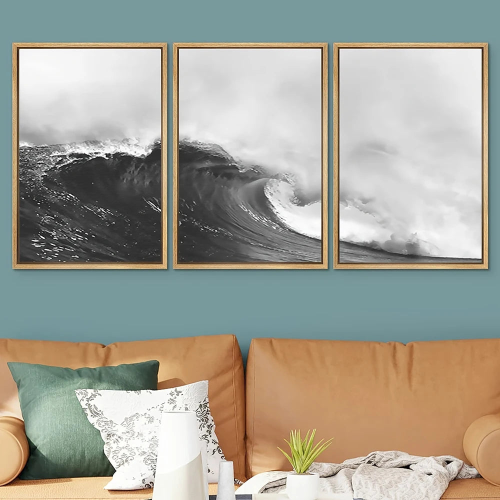 Three framed black and white wave prints on a wall above a brown sofa with decorative pillows and a plant.