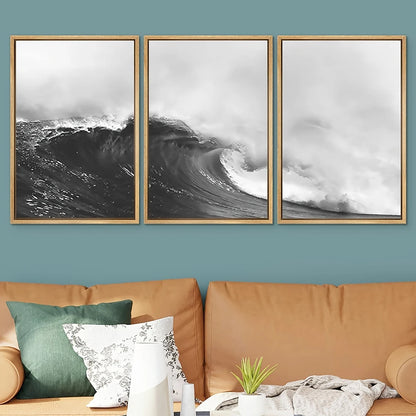 Three framed black and white wave prints on a wall above a brown sofa with decorative pillows and a plant.