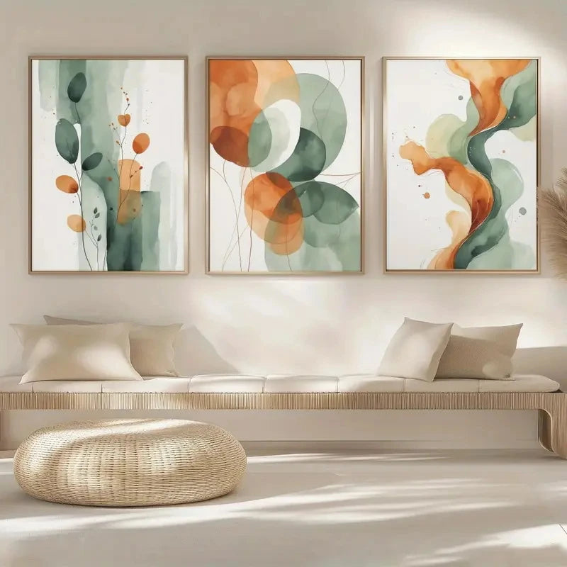 Three abstract art pieces in a living room setting with a sofa and ottoman.
