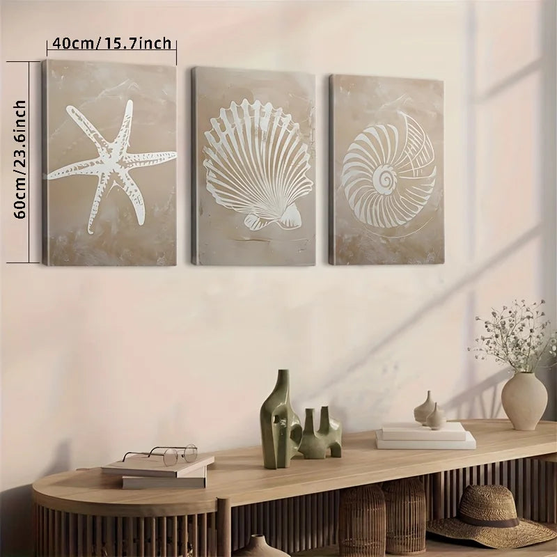 Three wall art pieces with starfish, shell, and spiral design on a wall above a wooden console table.