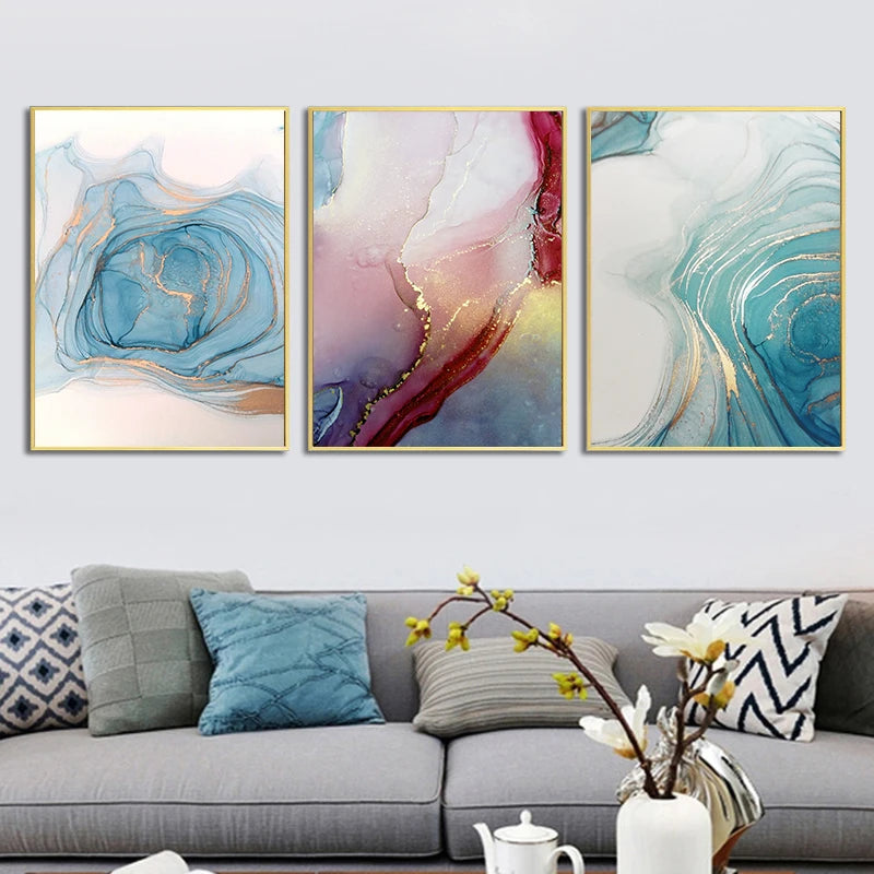 Three abstract wall art pieces above a gray sofa with decorative pillows.