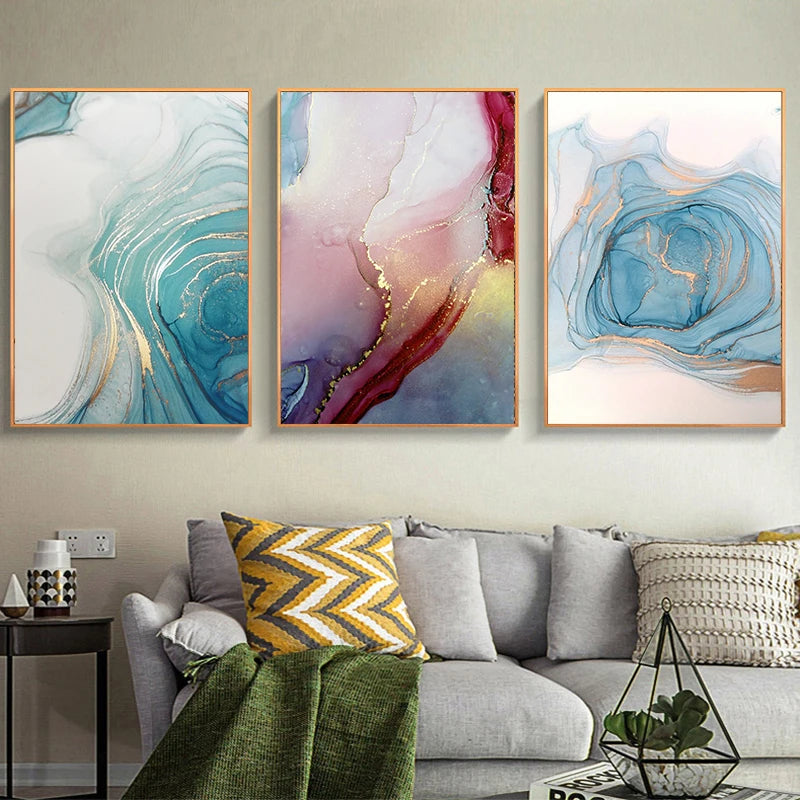 Three abstract art pieces on a wall above a sofa with decorative pillows.
