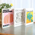 Three books on a reflective surface with 'Yayoi Kusama', 'Pablo Picasso', and 'Vincent Van Gogh' covers.