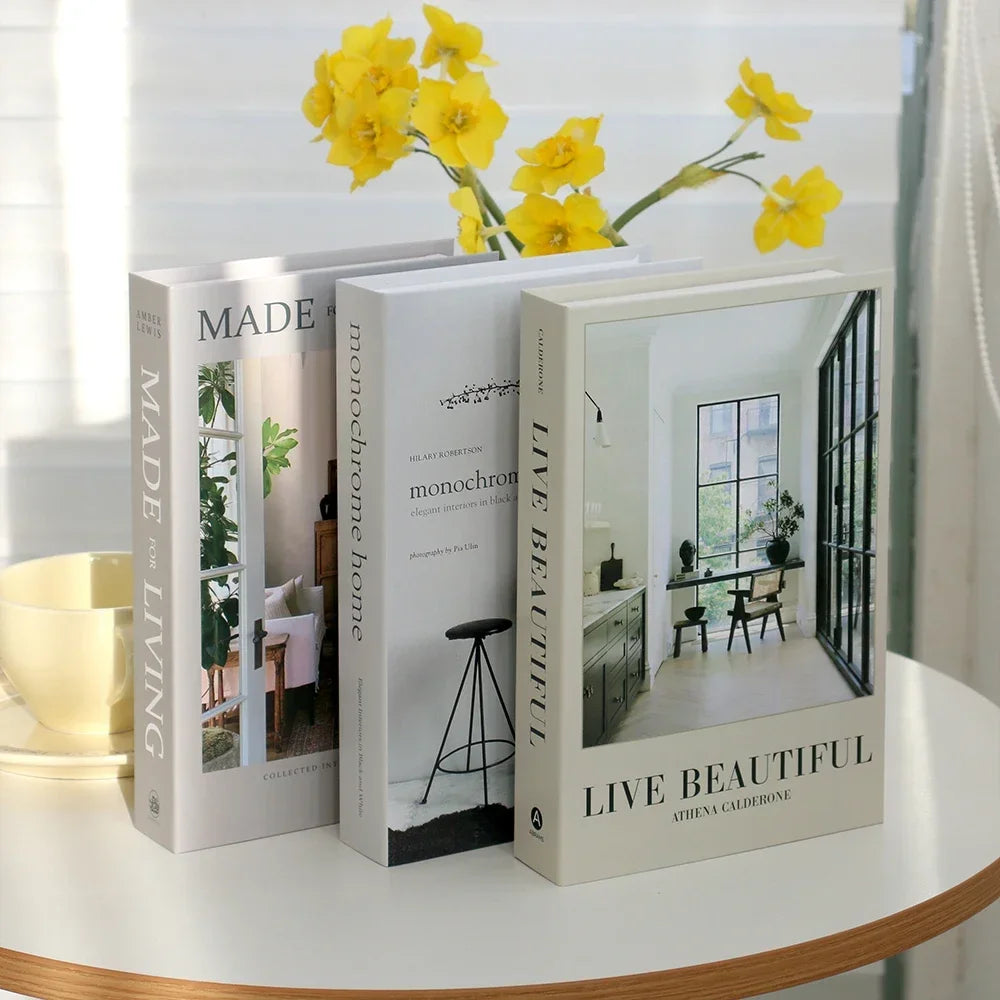 Three books on a table with yellow flowers above them