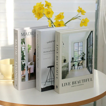 Three books on a table with yellow flowers above them