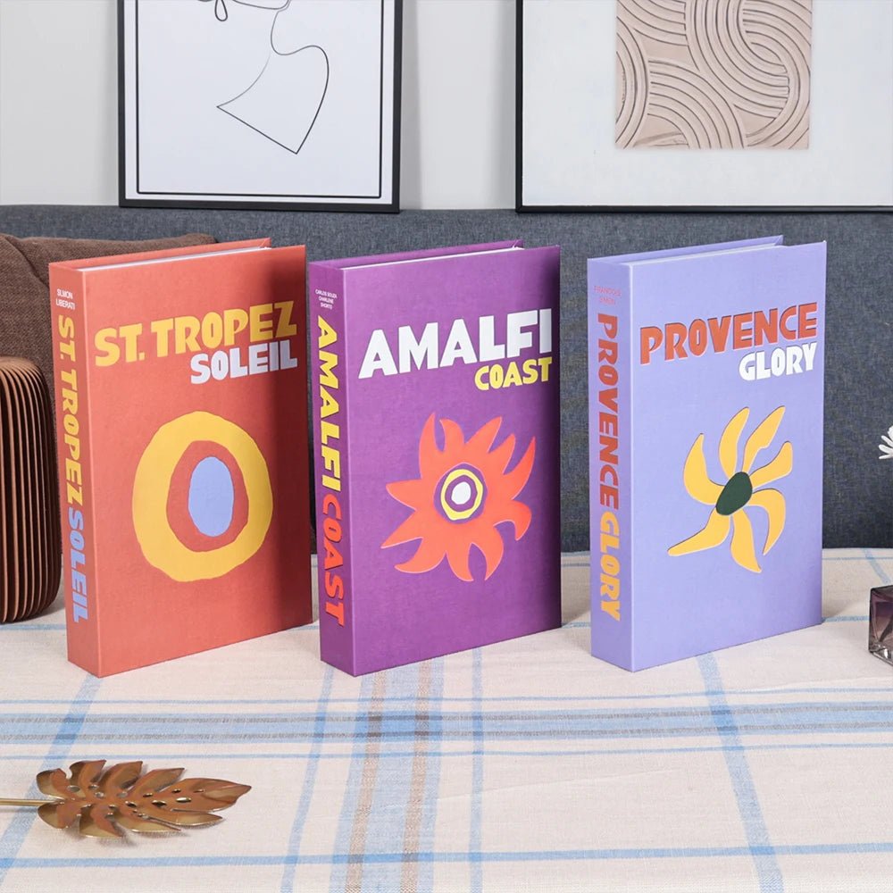 Three colorful books titled 'St. Tropez Soleil', 'Amalfi Coast', and 'Provence Glory' on a table.