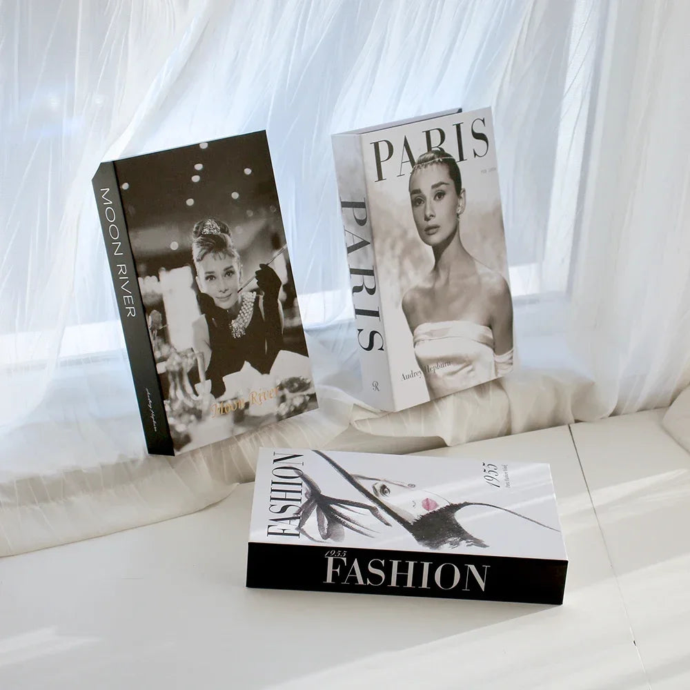 Three books titled 'Moon River', 'Paris', and 'Fashion' on a white surface with a sheer curtain background.