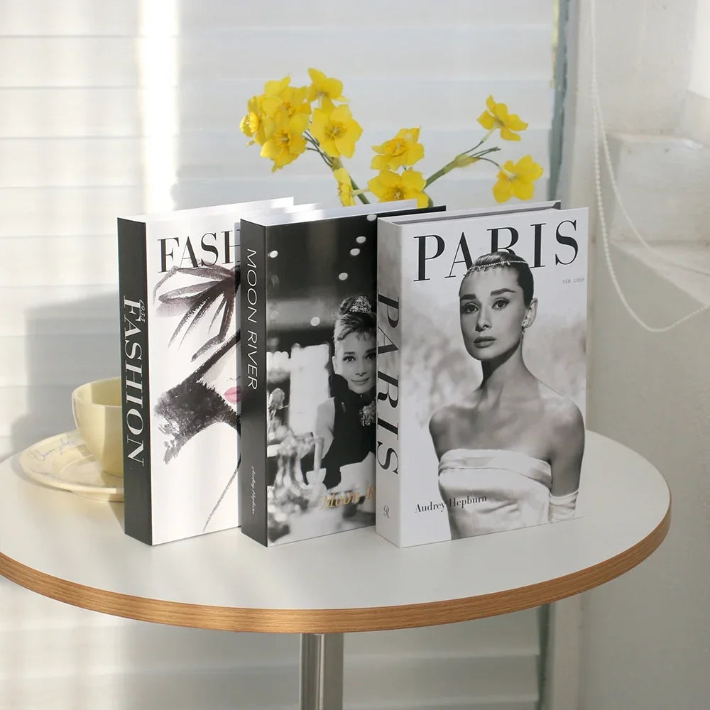 Three books on a table with a cup and yellow flowers in the background