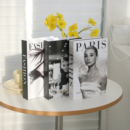 Three books on a table with a cup and yellow flowers in the background