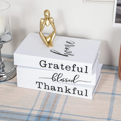 Stack of white boxes with motivational phrases on a table with a gold sculpture and candle in the background.