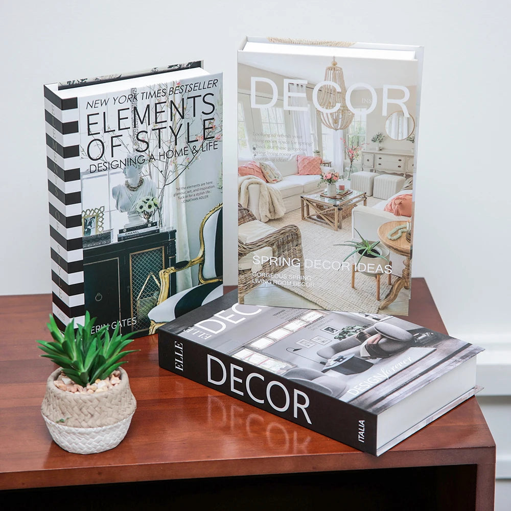 Three books on interior design on a wooden surface with a plant.