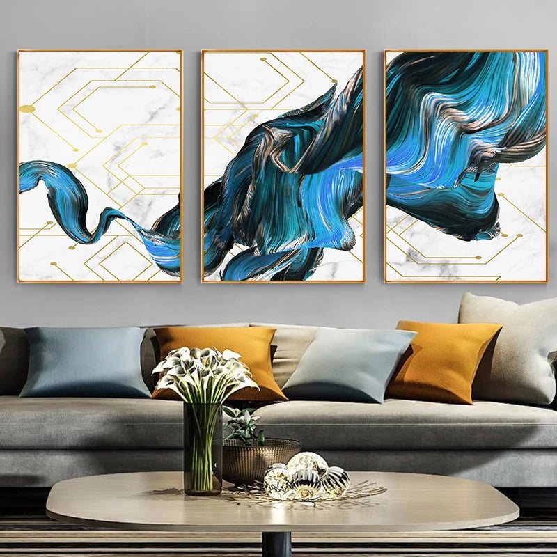Three abstract art pieces on a wall above a sofa with decorative pillows.