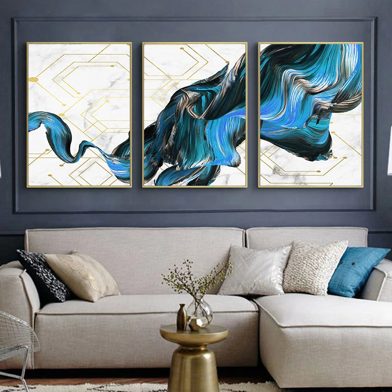 Three abstract art pieces on a wall above a sofa with decorative pillows.