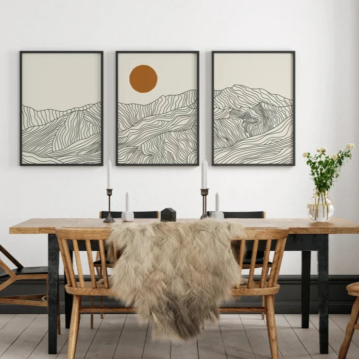 Dining room with wooden table, chairs, and wall art depicting mountains and a sun.