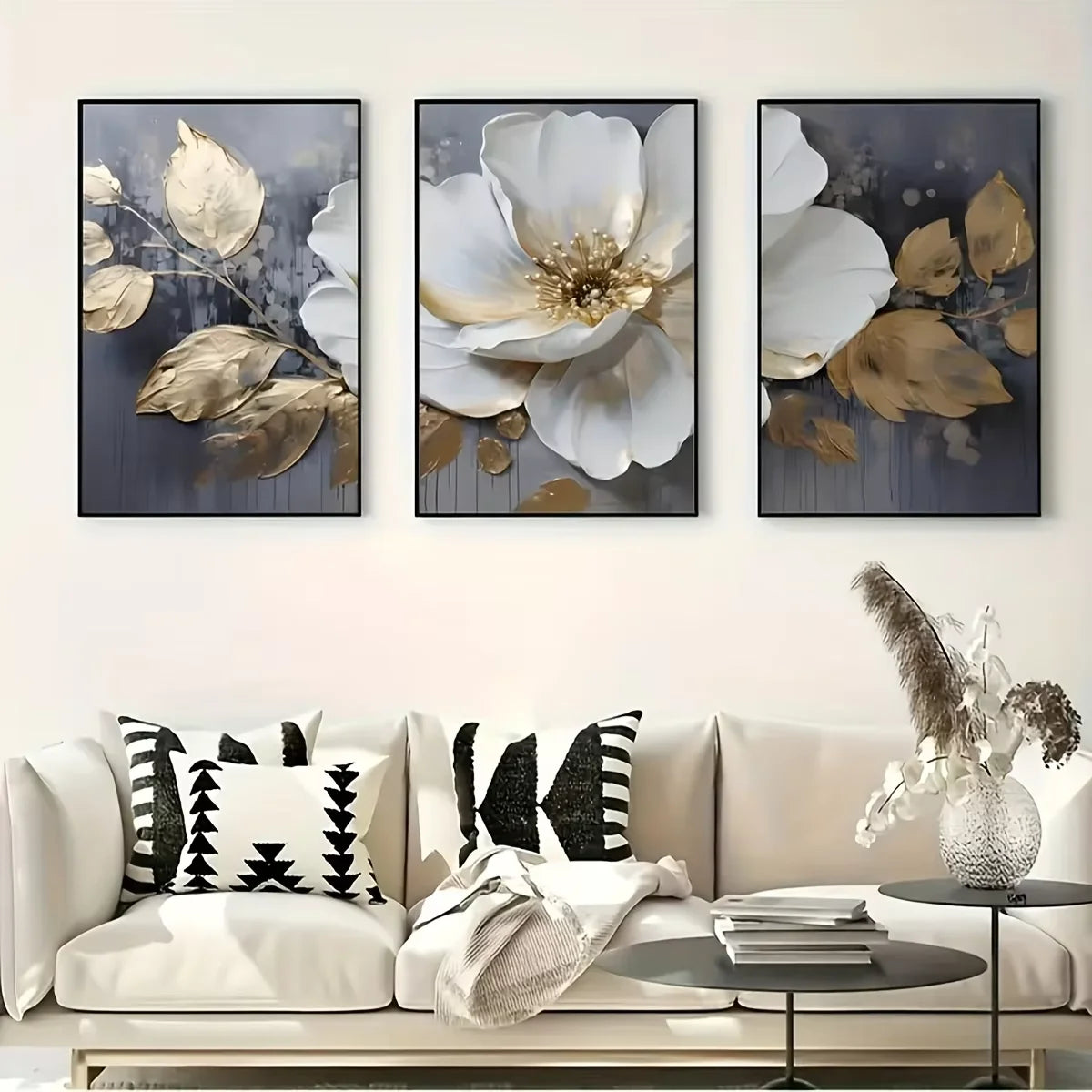Three floral art pieces above a sofa with decorative pillows and a coffee table.