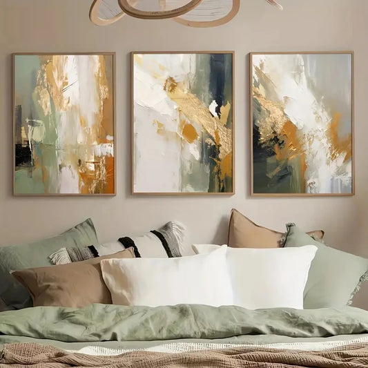 Three abstract art pieces on a wall above a sofa with pillows.