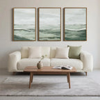 Modern living room with a white sofa, wooden coffee table, and three framed green landscape artworks.