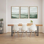 Dining room with a wooden table and white chairs, featuring three framed artworks on the wall.