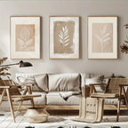 Living room with beige sofa, wicker chairs, and framed leaf prints on the wall.