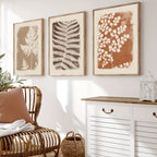 Living room with wicker chair, white cabinet, and framed botanical prints on the wall.