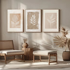 Three framed leaf prints on a wall with wooden furniture and plants in a room.