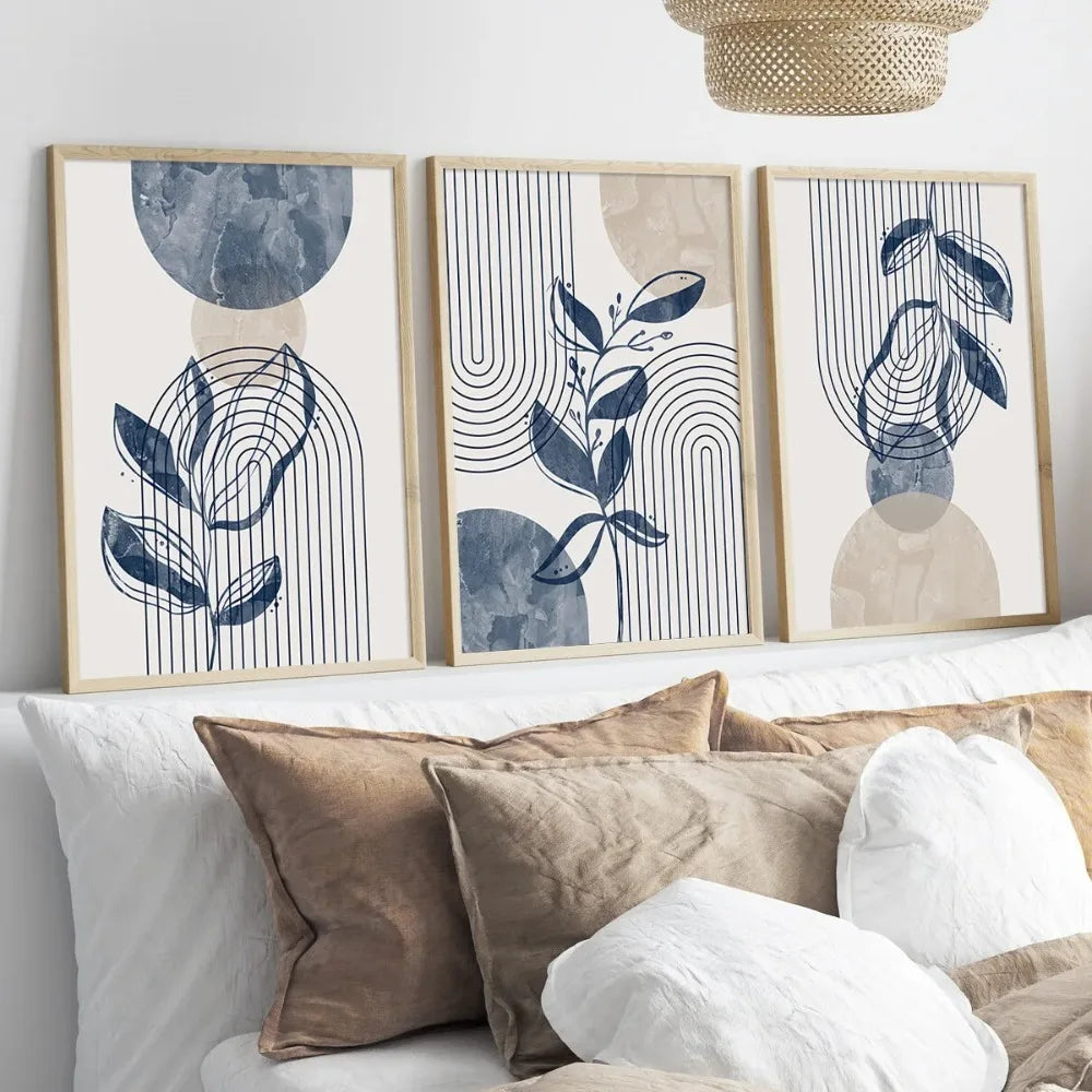 Three framed abstract art pieces on a wall above a sofa with pillows.
