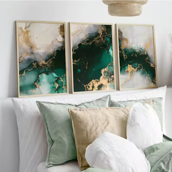 Three abstract art pieces on a wall above a sofa with decorative pillows.