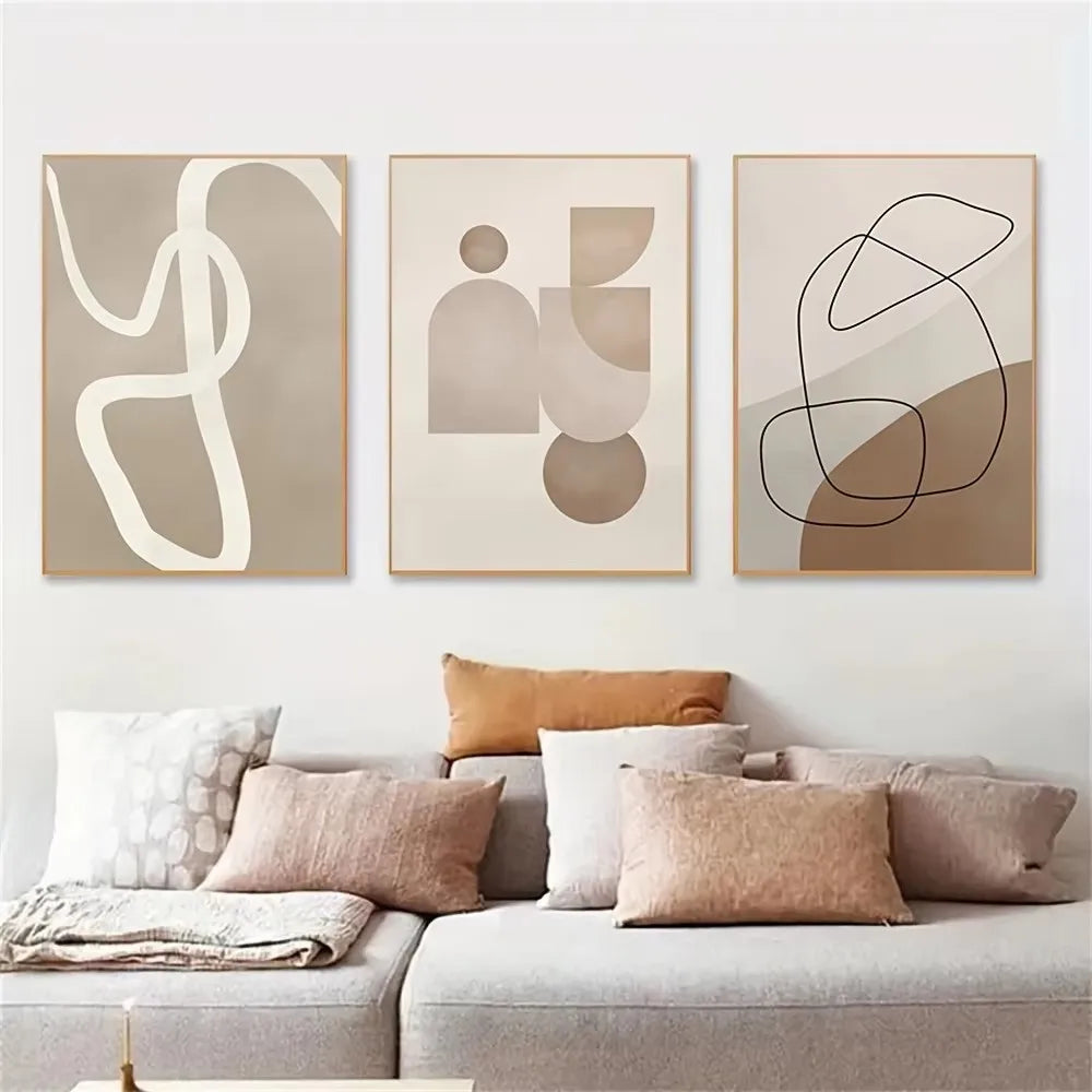 Abstract art prints on a wall above a sofa with cushions.