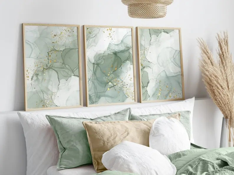 Three framed abstract art pieces on a wall above a sofa with decorative pillows.