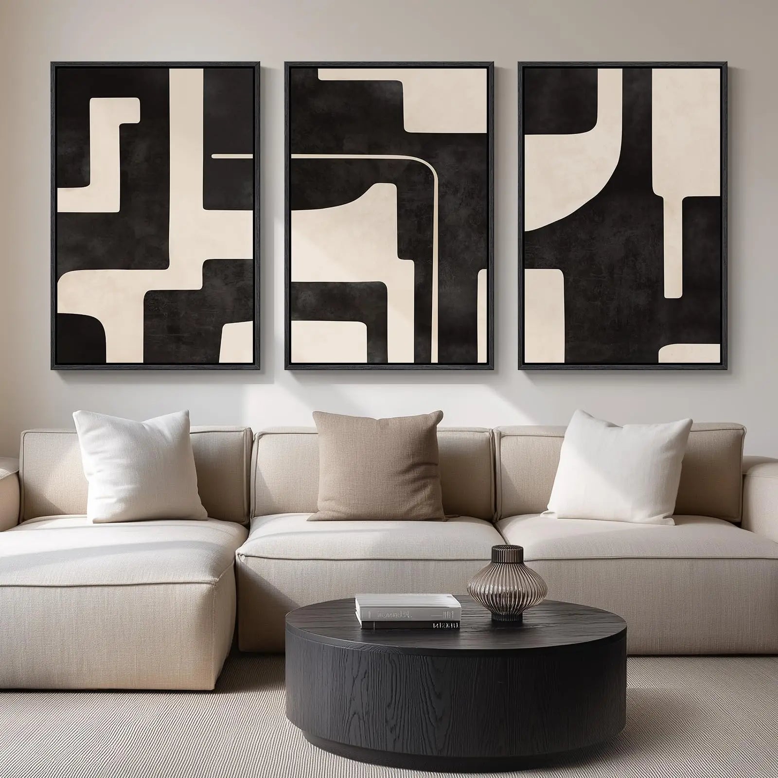 Modern living room with a beige sectional sofa, abstract art on the wall, and a round dark coffee table.