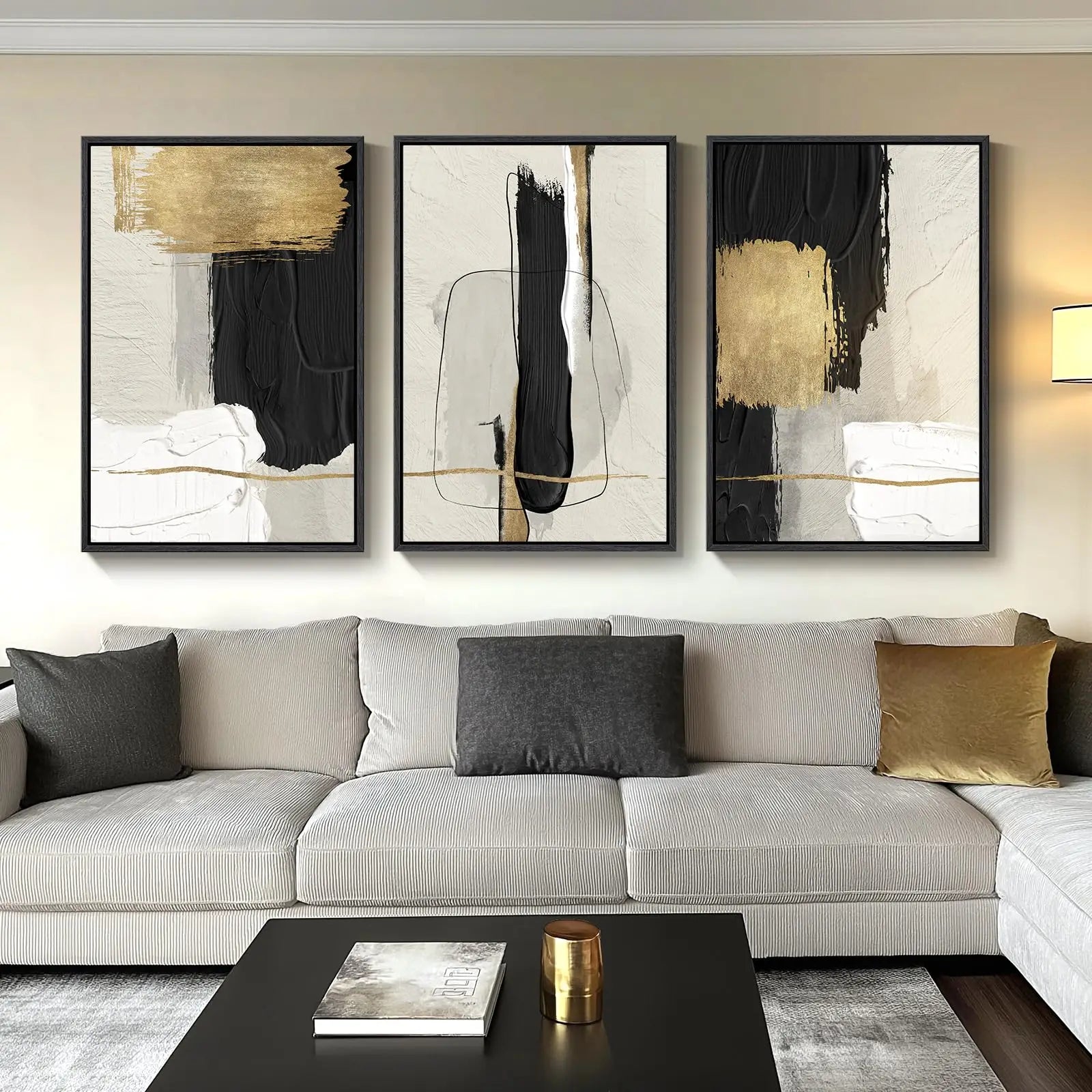 Three abstract art pieces on a wall above a sofa with decorative pillows.