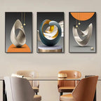 Three abstract wall art pieces above a dining table with chairs.