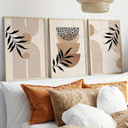 Three abstract wall art pieces above a sofa with decorative pillows.