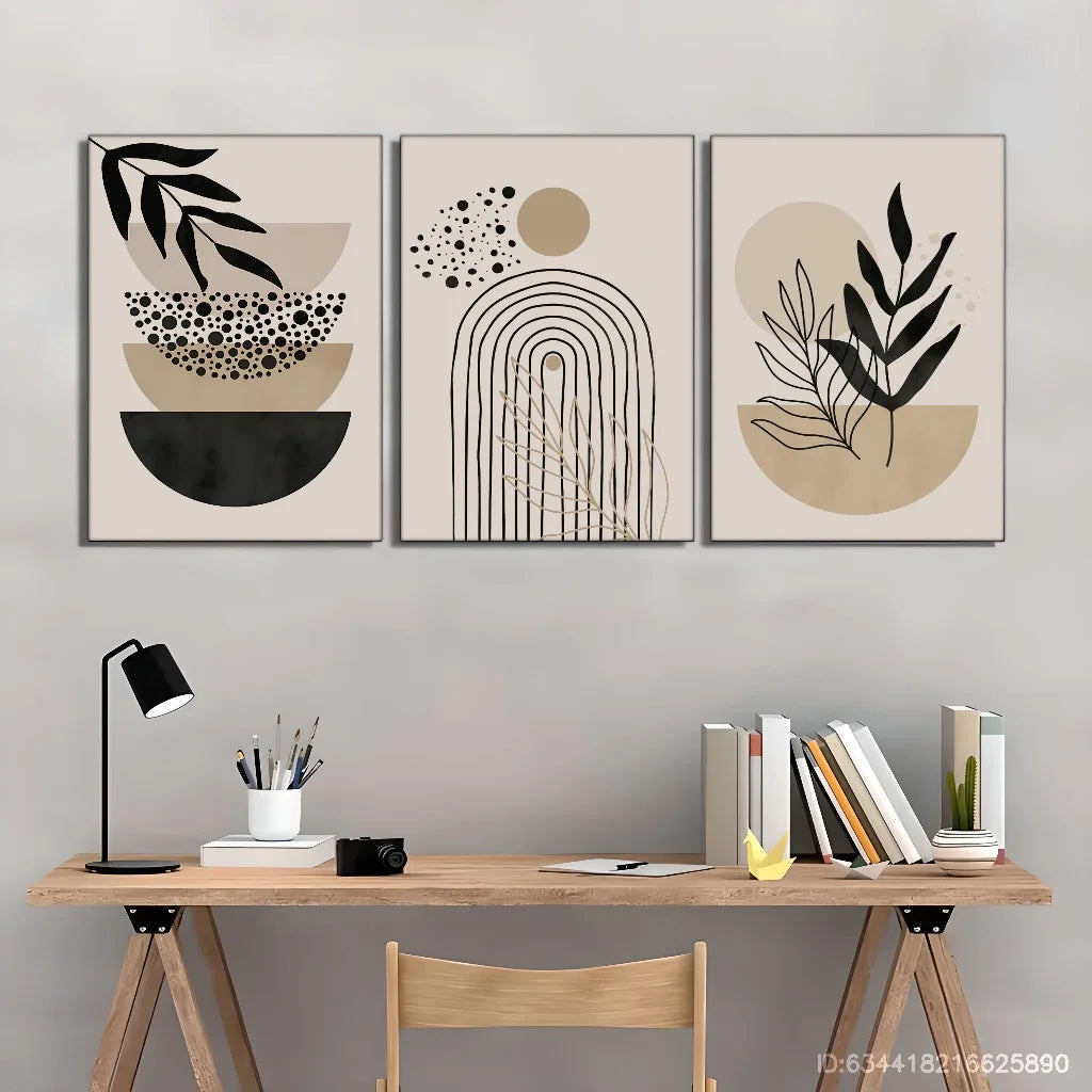Three abstract wall art pieces above a wooden desk with books and a lamp.