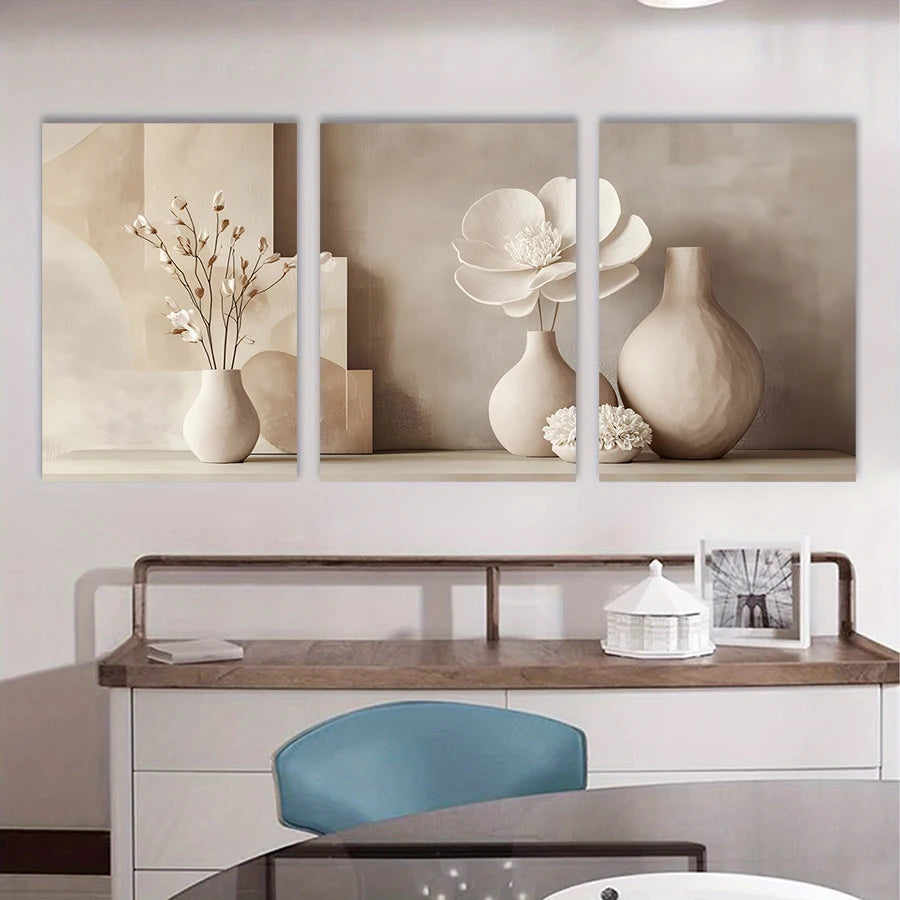 Three framed artworks of floral and vase arrangements on a wall above a desk.